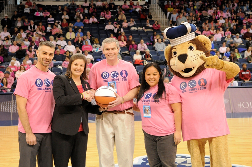 Dr. Jason McHugh, Dr. Michael Simpson, and Dr. Jocelyn Ricasa (all in pink) accept the game ball. 